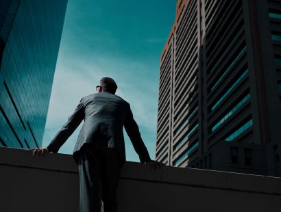 Business, man and thinking at city on rooftop about career or future with goal in company. Professional, person and skyscraper on roof is standing with vision or hope for decision as leader at work.