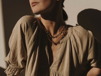 Young pretty woman in neutral beige linen sundress, dress in sun light shadows. Elegant luxury bohemian aesthetic lifestyle trendy stylish composition. Fashion clothes with sunlight shadow reflections